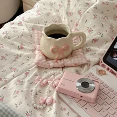 a laptop computer sitting on top of a bed next to a pink camera