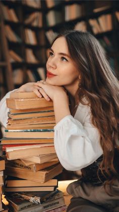 a woman sitting in front of a stack of books