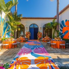 an outdoor dining area with tables and chairs decorated in bright colors, surrounded by palm trees