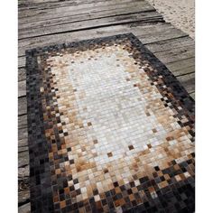 an area rug made out of different colored tiles on a wooden deck at the beach