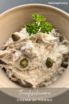 a white bowl filled with cream cheese and pistachioine sauce, topped with green sprigs