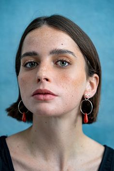 a woman with brown hair wearing red earrings