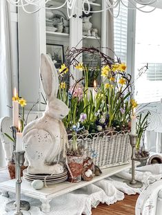 a basket filled with flowers sitting on top of a table next to a bunny statue