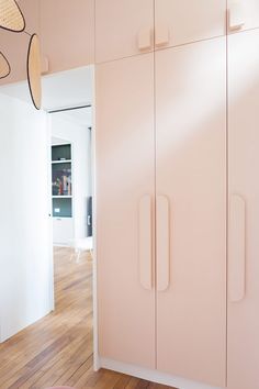 a room with pink cupboards and wooden flooring in front of a white wall