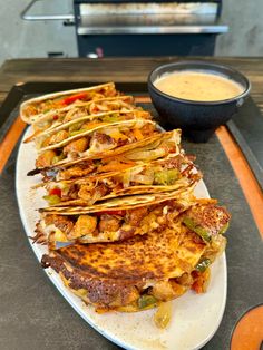 several quesadillas on a plate with a bowl of salsa in the background