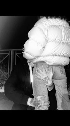 a man is covering his face while sitting on the ground in front of a fence