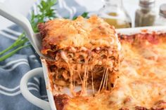 a slice of lasagna being lifted from a casserole dish with parmesan cheese