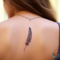 the back of a woman's neck with a feather tattoo on her left shoulder