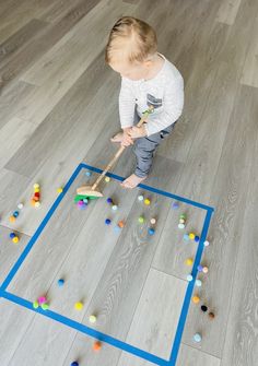 a toddler is playing with colored balls on the floor in front of a blue square