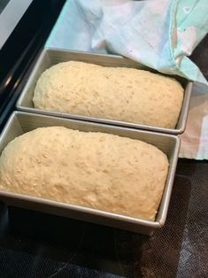 two metal pans filled with bread sitting on top of a counter