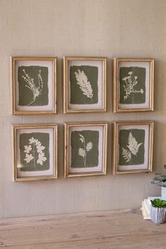 four framed pictures hang on the wall above a wooden table