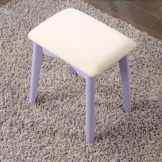 a white and purple stool sitting on top of a carpeted floor next to a rug