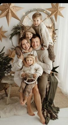 a family posing for a photo in front of a christmas tree with stars on the wall