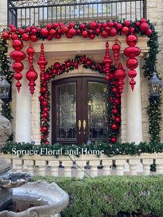 an entrance decorated with red ornaments and greenery for the holiday season is displayed in front of a building