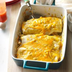 a casserole dish with meat and cheese in it sitting on a table next to an orange juice