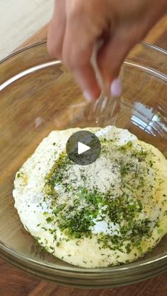 someone is adding seasoning to an omelet in a glass bowl on a wooden table