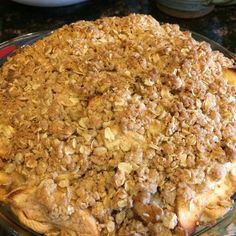 a pie with crumbled toppings sitting on top of a glass plate in front of a stove