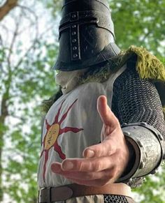 a close up of a person wearing a suit of armor and holding his hand out