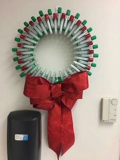 a christmas wreath with green and red lights hanging on the wall next to an electrical outlet