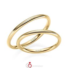 two gold wedding bands with engraved engraving on the sides, set against a white background