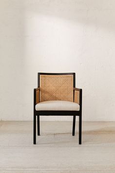 a chair sitting in front of a white wall with a light on it's side