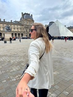 a woman holding the hand of another person in front of a building with a pyramid