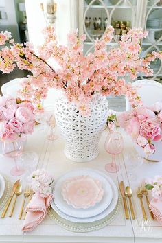 the table is set with pink flowers and place settings