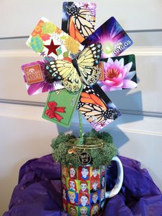 a coffee cup filled with lots of colorful cards and flowers on top of a purple table cloth