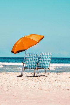 two chairs and an umbrella on the beach