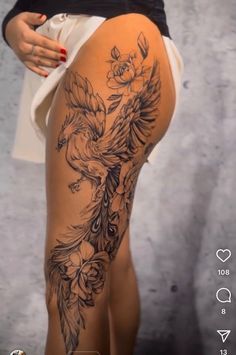 a woman is showing off her thigh with flowers and birds tattooed on the side of her leg