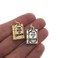 the book of mormon charm is in someone's hand and it says, the book of mormon