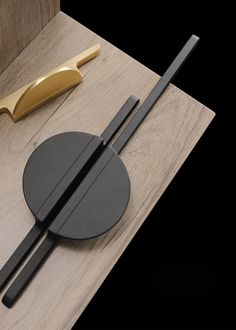 two chopsticks on a wooden table next to a knife and some sort of object