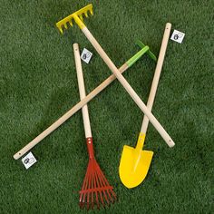 four garden tools laid out in the grass with numbered labels on them, including shovels and rakes