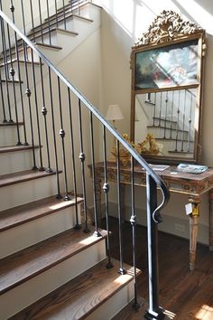 a mirror sitting on top of a stair case next to a table with a lamp