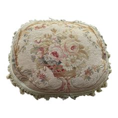 an embroidered pillow with flowers and fringes on the bottom, sitting on a white surface