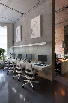 there are many computers on the desks in this large office space, all lined up against the wall