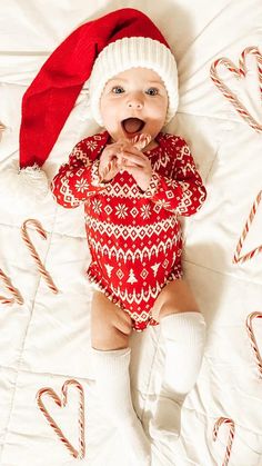 a baby wearing a santa hat and holding a candy cane in it's mouth