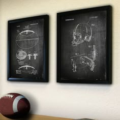 two footballs are hanging on the wall next to a chalkboard with drawings of helmets