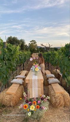 a woman sitting at a table in the middle of a field with hay bales