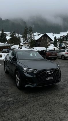 an audi car parked in a parking lot with snow on the ground and mountains in the background