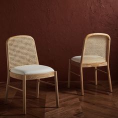 two chairs sitting next to each other in front of a red wall and wooden floor