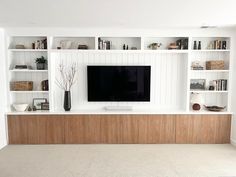 a large flat screen tv sitting on top of a wooden shelf in a living room