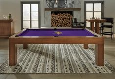 a pool table in the middle of a room with chairs and tables around it, next to a fireplace