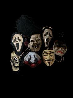 several masks with different facial expressions and hair are shown against a black background in this image