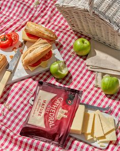 a picnic table with bread, cheese, tomatoes, and green apple slices on it