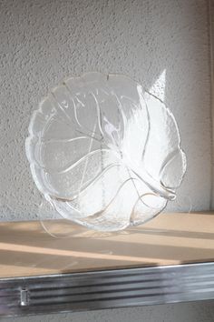 a clear glass plate sitting on top of a metal shelf next to a white wall