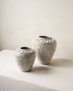 two white vases sitting on top of a bed