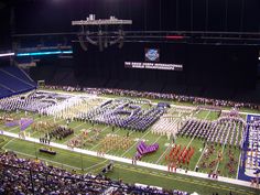 a marching band performing in front of an audience at a football game on the field