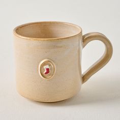 a coffee cup with a red heart on the side and a small hole in the middle