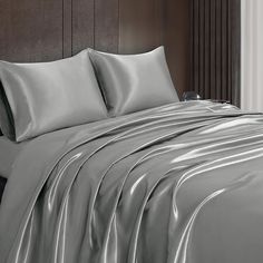 a bed covered in silver sheets and pillows